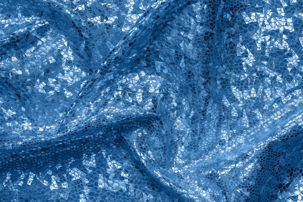Tessuto blu con pieghe ed effetto olografico. Priorità bassa o struttura geometrica astratta