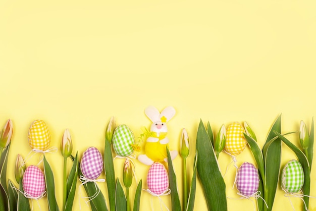 Tessuto coniglio souvenir uova e fiori su sfondo giallo spazio di copia Sfondo per biglietto di auguri per Pasqua Elementi decorativi e fiori primaverili Incontro primaverile