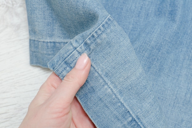 Tessuto denim in mano femminile. Parte di abbigliamento