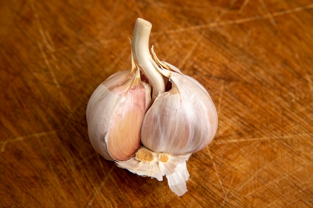 Testa d'aglio non sbucciata isolata sulla tavola di legno