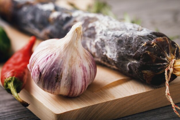 Testa d'aglio su un tagliere con salsiccia affumicata