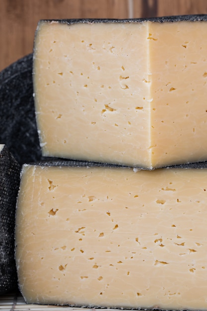 Testa rotonda di formaggio a pasta dura con fetta tagliata su legno