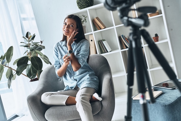 Testare il prodotto di bellezza. Attraente giovane donna che applica nuovi cosmetici mentre realizza nuovi video al chiuso