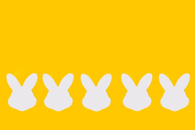 Teste di coniglio di carta bianca su sfondo giallo con spazio per la copia