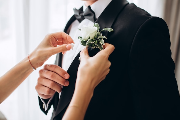 Testimoni dello sposo alla moda che aiutano sposo felice che si prepara al mattino per la cerimonia di nozze. uomo di lusso in tuta in camera. giorno del matrimonio.