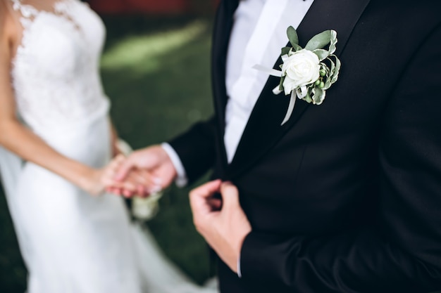 Testimoni dello sposo alla moda che aiutano sposo felice che si prepara al mattino per la cerimonia di nozze. uomo di lusso in tuta in camera. giorno del matrimonio.