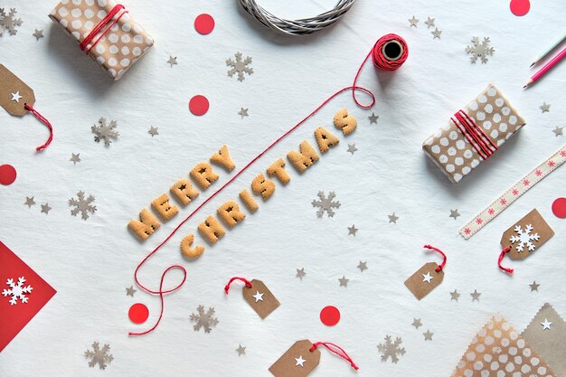 Testo Buon Natale fatto di lettere di biscotti. Creative Xmas flat lay con scatole regalo e decorazioni in carta artigianale.