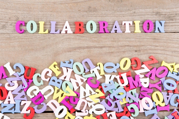 Testo Collaborazione di lettere di legno colorate su uno sfondo di legno