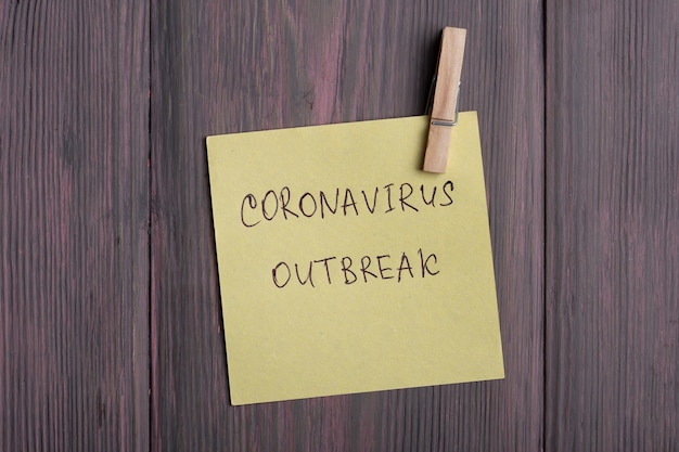Testo Coronavirus Outbreak su una nota adesiva che si blocca con una molletta su sfondo di legno - concetto sanitario e medico