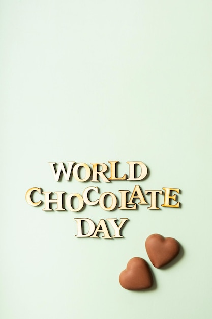 Testo della giornata mondiale del cioccolato con vista dall'alto piatto al cioccolato su sfondo verde pastello