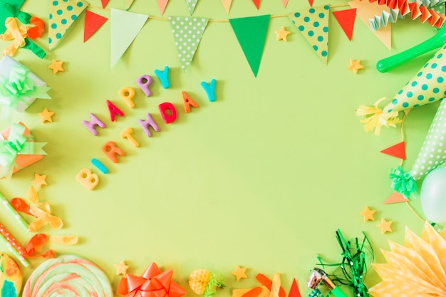 Testo di buon compleanno con accessori su sfondo verde