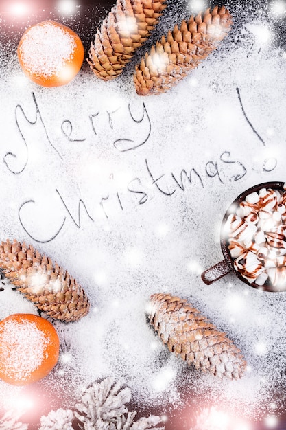 Testo fatto a mano di buon Natale sulla neve. Caramella gommosa e molle dolce dell'alimento di Natale con cioccolato in tazza marrone