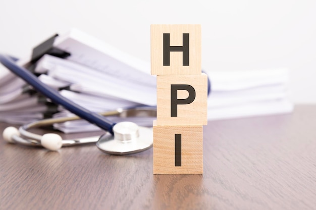 Testo HPI scritto su blocchi di legno vicino a uno stetoscopio su un concetto medico di sfondo cartaceo