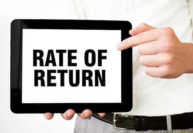 Testo RATE OF RETURN su display tablet in mani di uomo d'affari su sfondo bianco Concetto aziendale