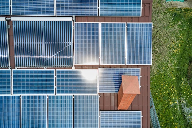 Tetto dell'edificio con file di pannelli fotovoltaici blu e collettori solari ad aria sottovuoto per il riscaldamento dell'acqua e la produzione di energia elettrica pulita ed ecologica Energia elettrica e termica rinnovabile a zero emissioni