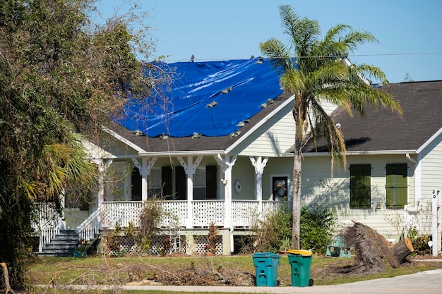 Tetto della casa che perde coperto con teloni protettivi contro le perdite di acqua piovana fino alla sostituzione delle tegole di asfalto Danni al tetto dell'edificio a seguito dell'uragano Ian in Florida