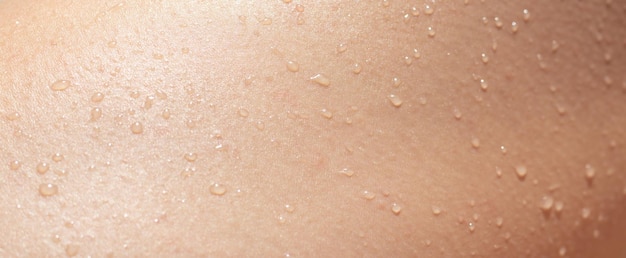 Texture della pelle femminile bagnata con gocce di liquido primo piano corpo umano abbronzato con gocce d'acqua