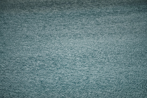 Texture di acqua calma blu scuro del lago. Increspature meditative sulla superficie dell'acqua. Fondo minimo della natura del lago blu profondo. Sfondo naturale di acqua turchese chiara e scura. Full frame di frammento di lago.