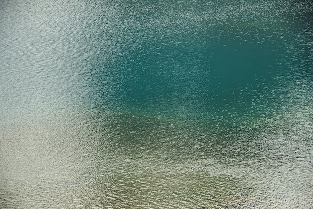 Texture di acqua calma verde blu del lago. Increspature meditative sulla superficie dell'acqua.