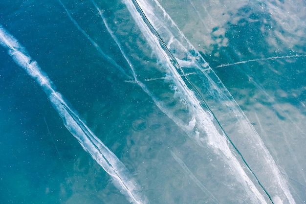 Texture di ghiaccio blu con crepe sul lago ghiacciato. Immagine macro. Sfondo della natura invernale