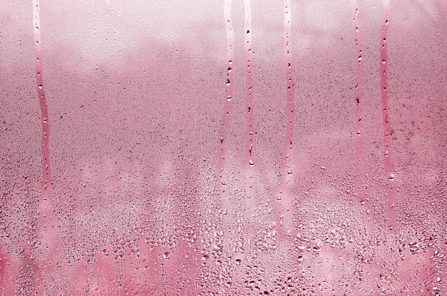 Texture di una goccia di pioggia su un'immagine di sfondo trasparente bagnata di vetro tonica in colore magenta viva di