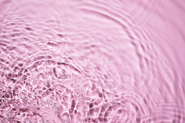 Texture superficiale dell'acqua rosa con spruzzi e bolle Sfondo astratto per i prodotti di bellezza