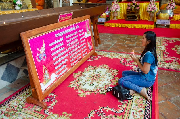 Thai donna seduta rispetto pregando grande statua del Buddha sdraiato in ubosot o chiesa al Wat Phra Non Chakkrasi Worawihan il 9 febbraio 2017 a Sing Buri Thailandia