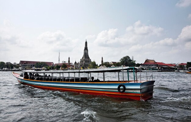 Thailandia, Bangkok, vista di un traghetto sul fiume Chao Praya e un tempio di Arun in background (Wat Arun Ratchawararam)