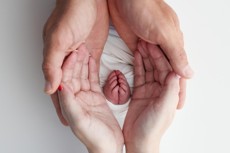 Photo the palms of the father the mother are holding the foot of the newborn baby in a white blanket feet of the newborn on the palms of the parents studio macro photo of a childs toes heels and feet