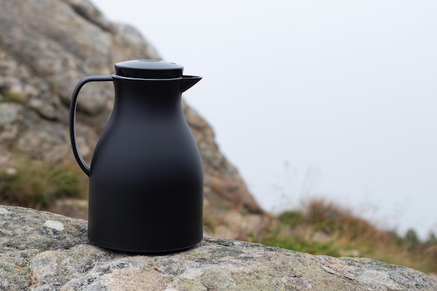 Thermos su rocce contro un paesaggio di montagna Concetto di viaggio o turismo Spazio esterno per la copia