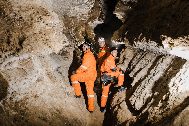 Three men strong physique explore the cave Men dressed in special clothes to pass through the cave and stopped looking at the map