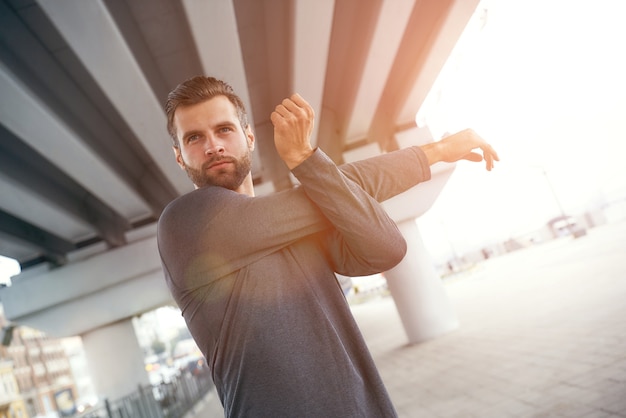 Ti sei allenato oggi ritratto di giovane uomo barbuto in abiti sportivi che allunga il braccio mentre?