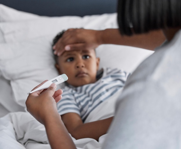 Ti senti un po' caldo Inquadratura di un bambino sdraiato a letto e che si sente male mentre sua madre gli controlla la temperatura