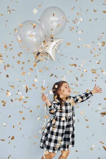 Tiene palloncini Bambina felice in piedi e divertirsi al chiuso alla festa di compleanno