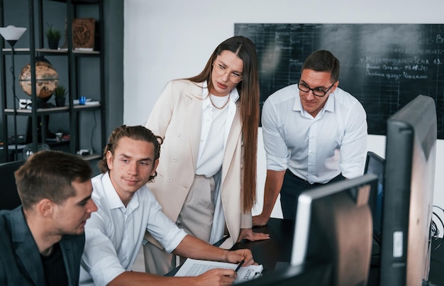 Tiene traccia dei grafici Il team di agenti di cambio lavora in un ufficio moderno con molti schermi