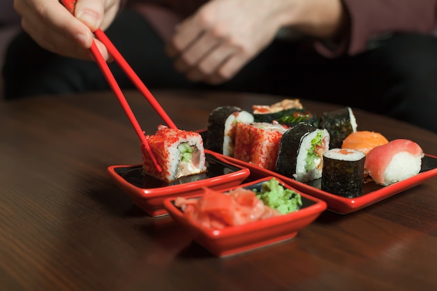 Tieni il sushi roll con le bacchette.