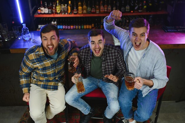 Tifosi di calcio al bar Tifosi di calcio felici che si acclamano al bar e bevono birra mentre il barista serve birra sullo sfondo