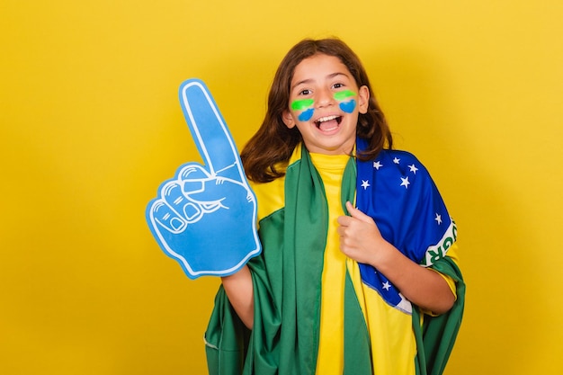 Tifoso brasiliano di calcio per bambini caucasici con dito in schiuma che celebra e fa festa alle Olimpiadi della Coppa del mondo