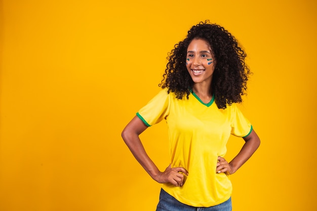 tifoso brasiliano. Fan della donna brasiliana che celebra sulla partita di calcio o di calcio su sfondo giallo. Colori del Brasile.