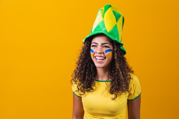 tifoso brasiliano. Fan della donna brasiliana che celebra sulla partita di calcio o di calcio su sfondo giallo con spazio di copia. Colori del Brasile.