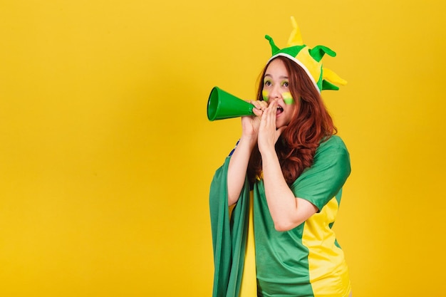 Tifoso di calcio brasiliano donna rossa caucasica che urla promozione utilizzando la foto pubblicitaria del mega telefono