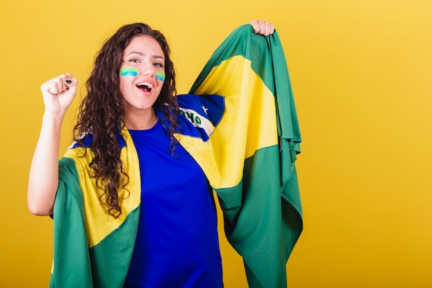 Tifoso di calcio donna brasile fan della coppa del mondo che tiene bandiera e tifo festeggiando e festeggiando ballando