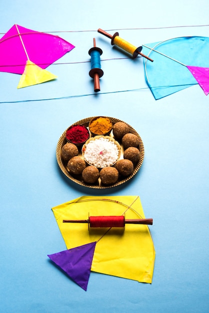 Til Gul OR Sweet Sesamo Laddu con modello in miniatura Fikri e Kite con haldi Kumkum e cristalli di zucchero per il festival Makar Sankranti su sfondo lunatico, messa a fuoco selettiva