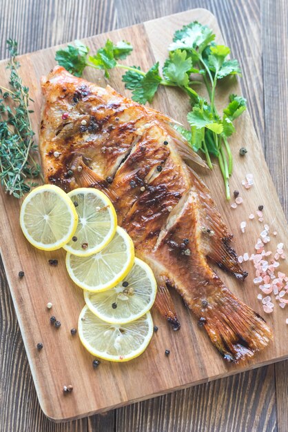 Tilapia arrostito con le erbe sul bordo di legno