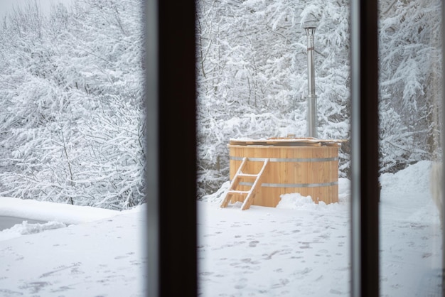 Tino caldo di legno sul terrazzo nevoso alle montagne