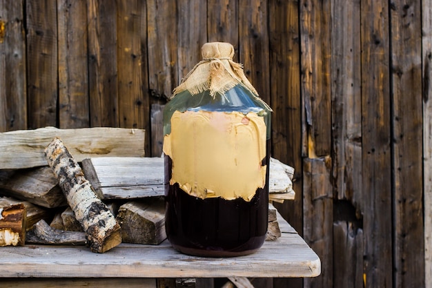 Tintura di betulla artigianale alcolica in una grande bottiglia di vetro su un tavolo di legno, ricetta popolare russa.