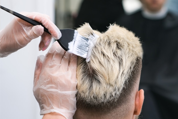 Tintura per capelli per un giovane in un parrucchiere. il maestro decolora i capelli della cliente