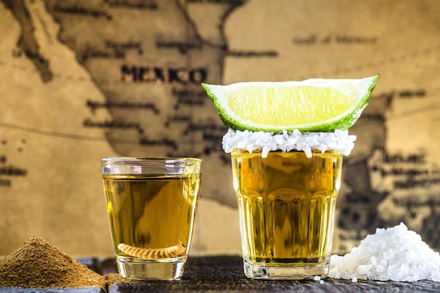 Tipiche bevande messicane, Mezcal con sale, pepe e larva accanto alla tequila con limone e sale, con mappa del Messico in superficie