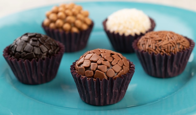 Tipici brigadeiros brasiliani, vari gusti su un piatto blu.