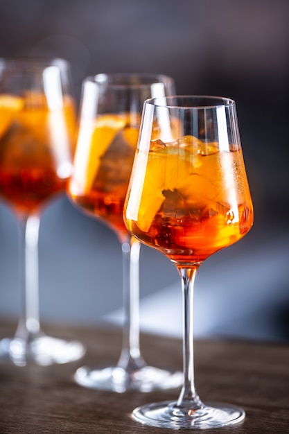 Tipico drink estivo aperol spritz servito in bicchieri da vino con aperol, prosecco, soda e una fetta di arancia.